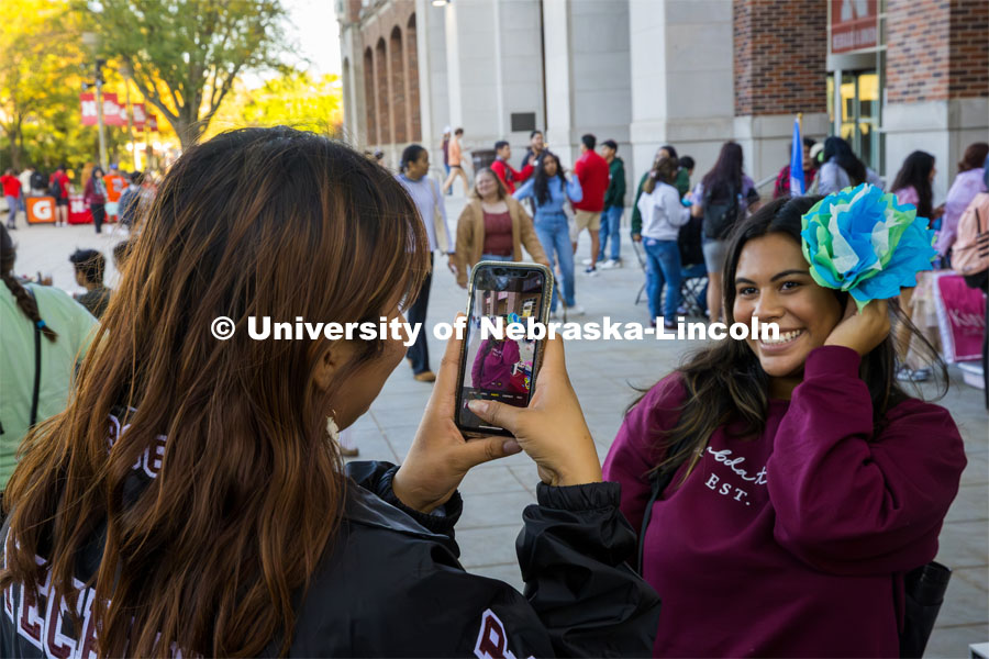 Lambda Theta Nu Sorority helped visitors make tissue paper flowers. A student models her creation. Fiesta on the green at the Nebraska Union Plaza. Fiesta on the Green is an annual Latino culture and heritage festival. October 5, 2023. Photo by Kristen Labadie / University Communication.